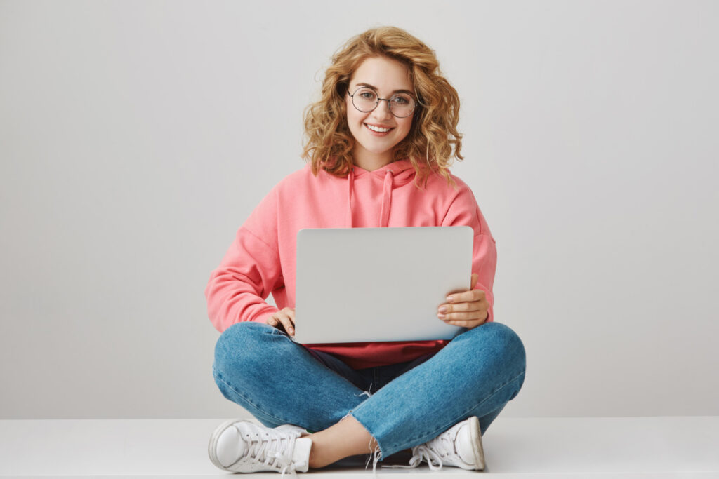 Étudiante souriante en train de suivre une formation en ligne avec son ordinateur portable sur Skilloza.